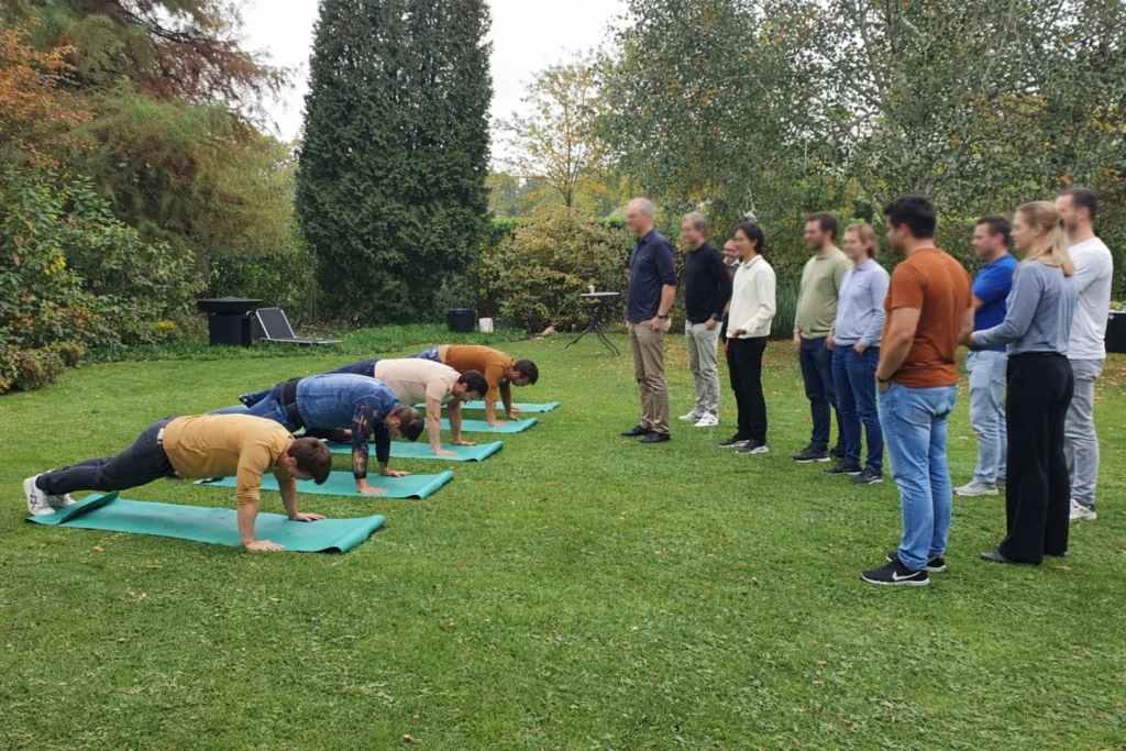 Teamleden doen push-ups in het park.